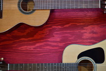 two acoustic guitars on red wooden background