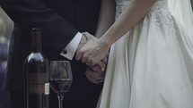 bride and groom holding hands and wine 