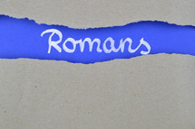 word Romans exposed under gray torn paper 