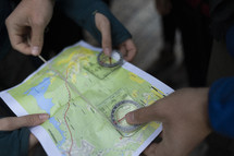 People huddled around a trail map holding a compass 