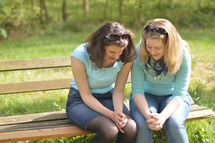 friends praying together on a park bench 