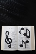 A Bible open to Psalms covered in musical notes.