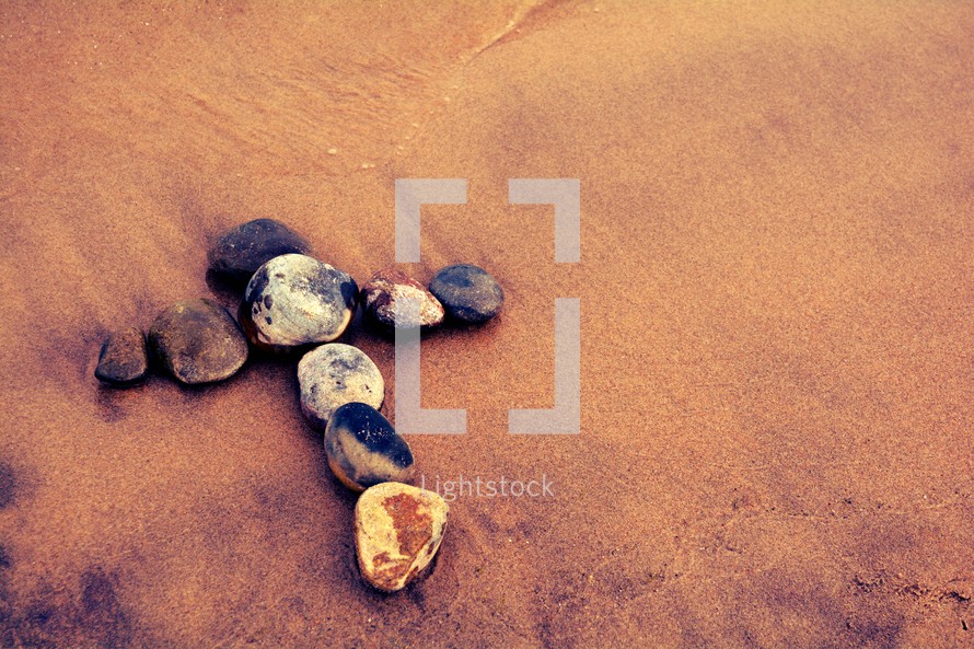 stones in the shape of a cross in the sand 