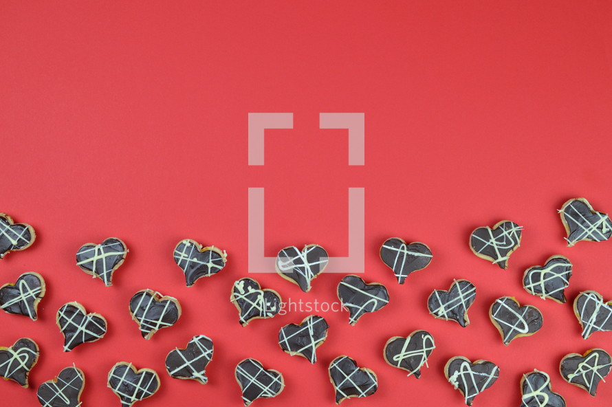 border out of home made heart shaped cookies with chocolate on red background