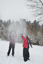 friends tossing snowballs into the air