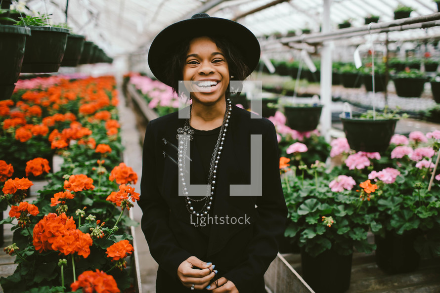 An African American woman in a black hat standing in a greenhouse 