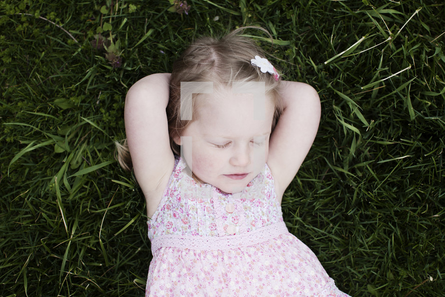 toddler girl lying in the grass with her eyes closed