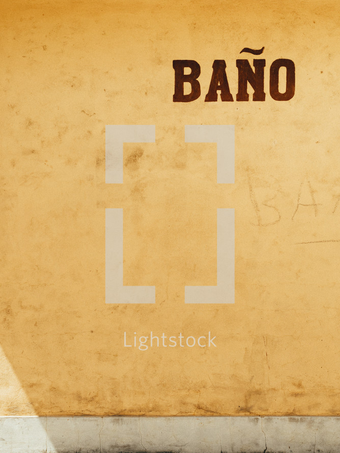 A stucco wall with the word "bano."