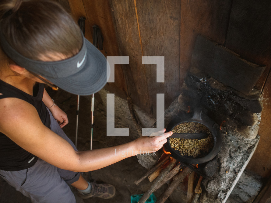 A woman cooks beans over a wood burning stove.
