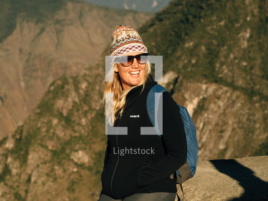 female hiker with a backpack, cap, and sunglasses 