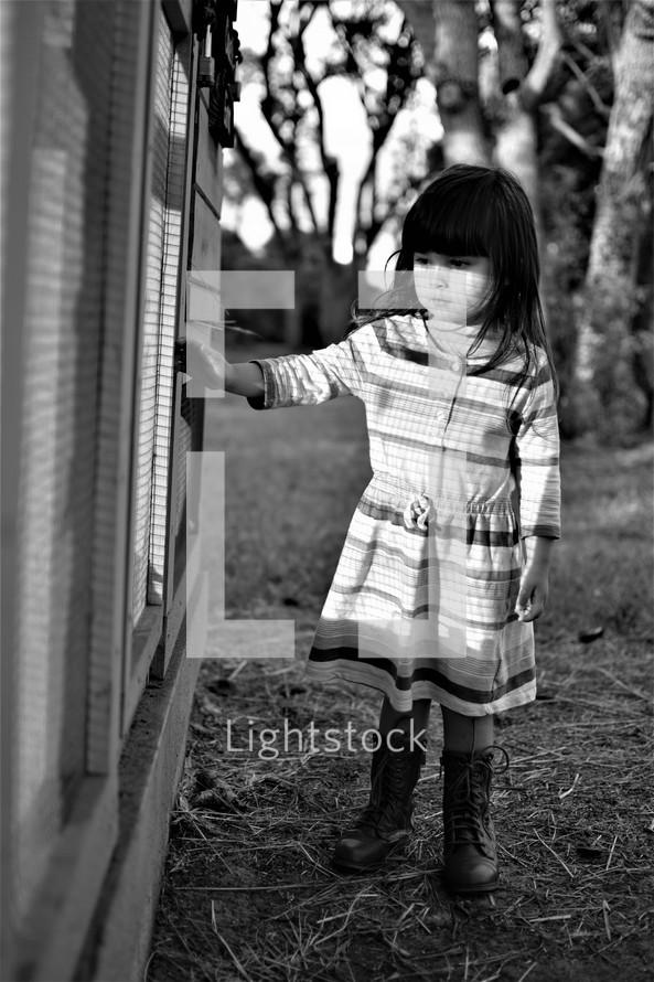 a girl looking into a chicken coup 