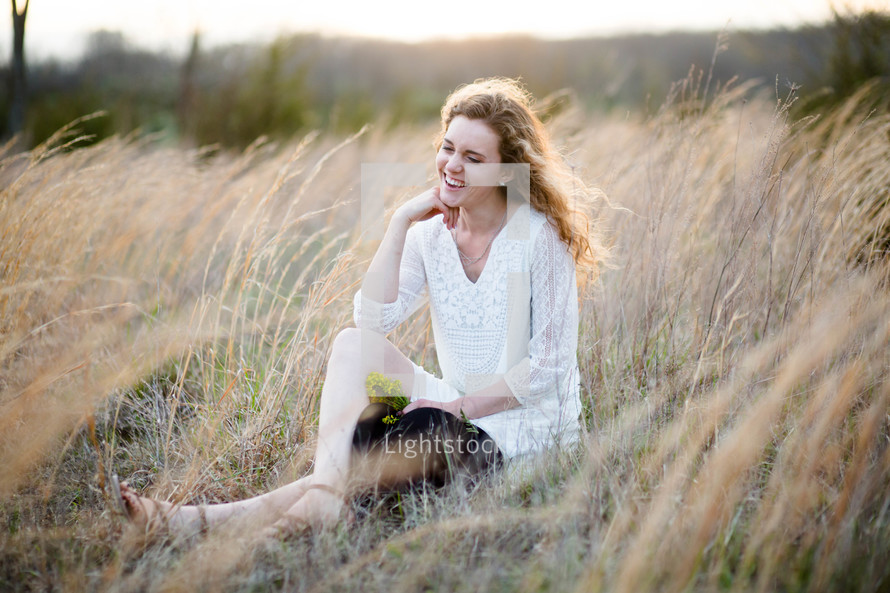 a woman sitting in a field of tall grasses 