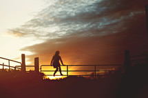 woman sitting on a fence watching a fiery sunset 