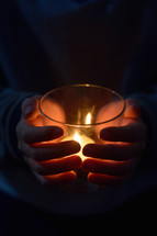 hands around a candle at a vigil 