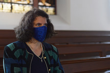 a woman wearing a face mask sitting in church pews 