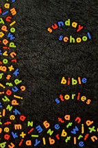 the words SUNDAY SCHOOL and BIBLE STORIES written with colorful magnetic letters on black ground 