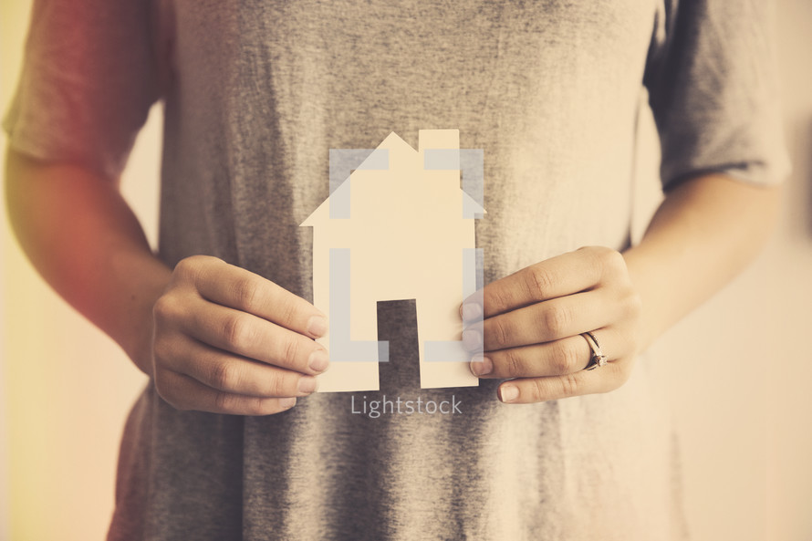 man holding a paper cutout of a house 