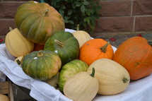 green, orange, and white pumpkins in a wagon 