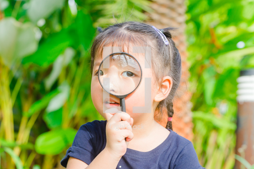 a toddler girl looking through a magnifying glass 