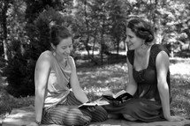 women reading Bibles on a blanket in the grass