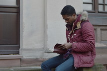 a man in a coat reading a Bible 