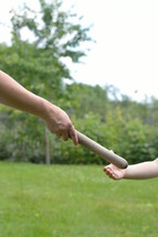 mother giving the relay baton to the next generation into her daughter's hand 