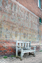 wooden bench against an old brick wall 