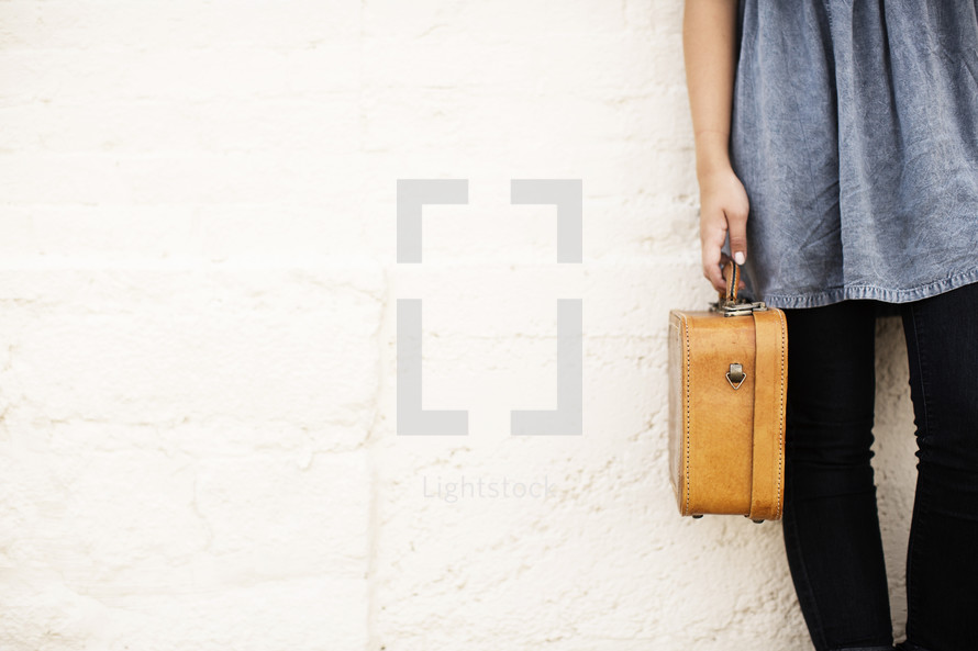 torso of a girl holding a suitcase 