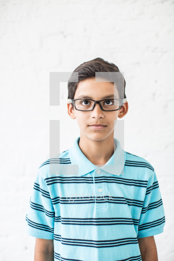 stoic face on a boy child with reading glasses 