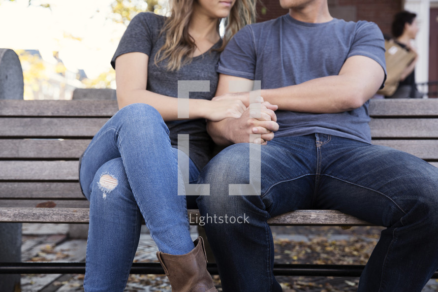 couple snuggling sitting on a bench 