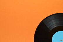old black vinyl record with blank cyan label on orange background