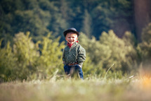Cute Little Happy Boy with Hat and Bandana in Green Summer Forest