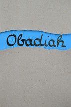 Obadiah - torn open kraft paper over blue paper with the name of the prophetic book Obadiah