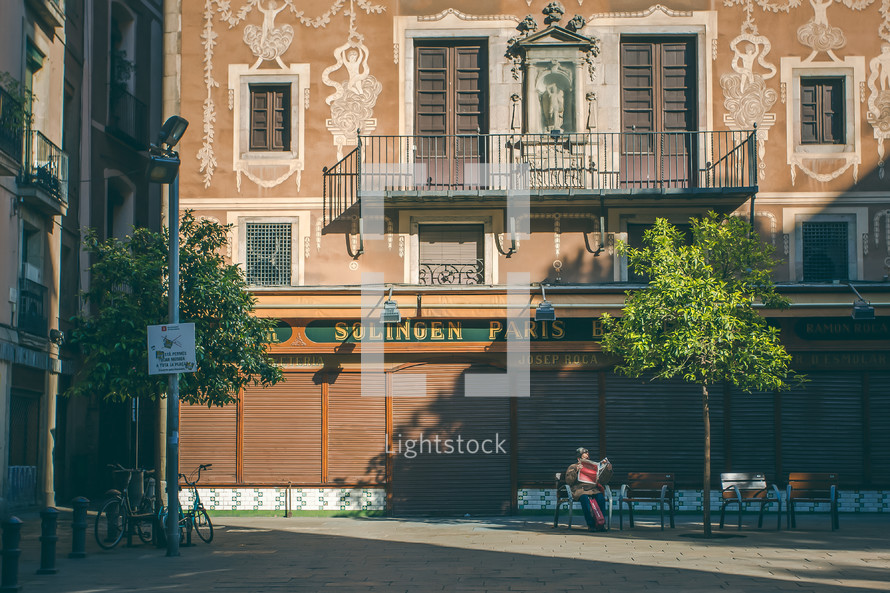 a woman reading a newspaper in a courtyard in Barcelona