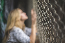 a woman clinging to a chain link fence 