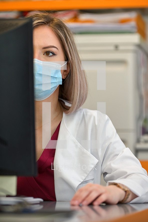 A Doctor In A Mask Works On A Computer