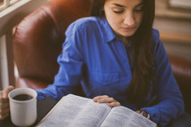 A woman reading a Bible drinking coffee