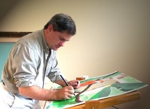 An Artist  with rolled up shirt sleeves works intently on a new painting at his easel in his art studio creating a new illustration.