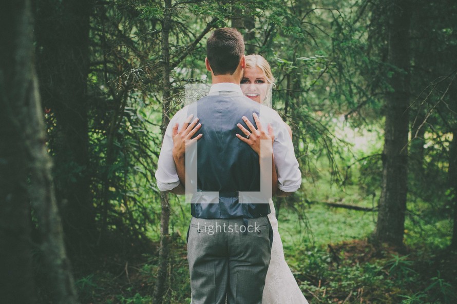 bride and groom hugging in the woods 
