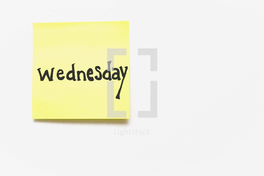 A yellow sticky note with "wednesday" written in black ink on a white background.