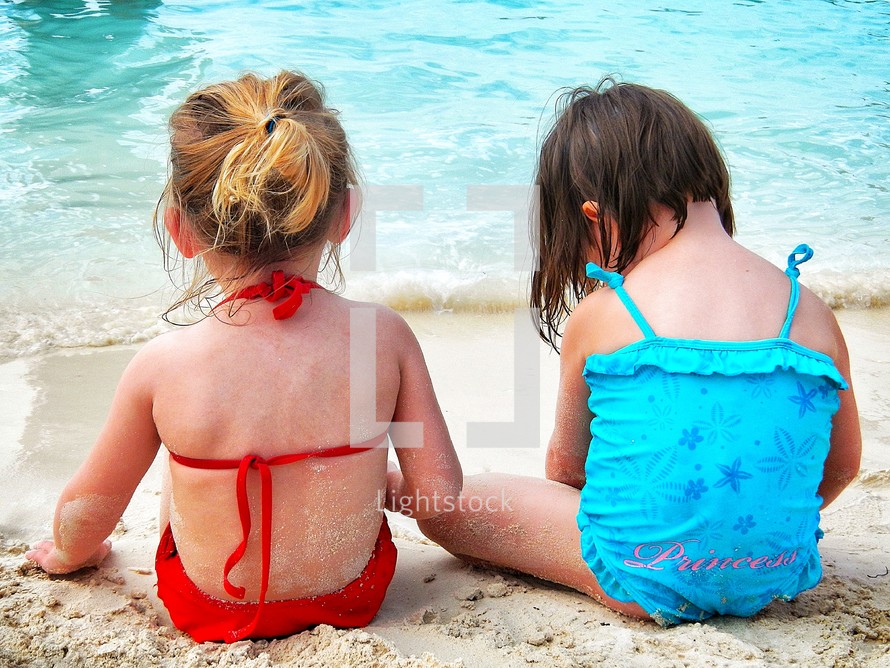 girls sitting on the beach in their bathing suits