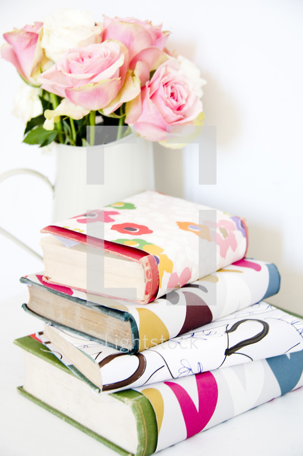vase of roses and books with book covers 
