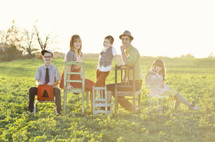 Family sitting on chairs in a meadow.