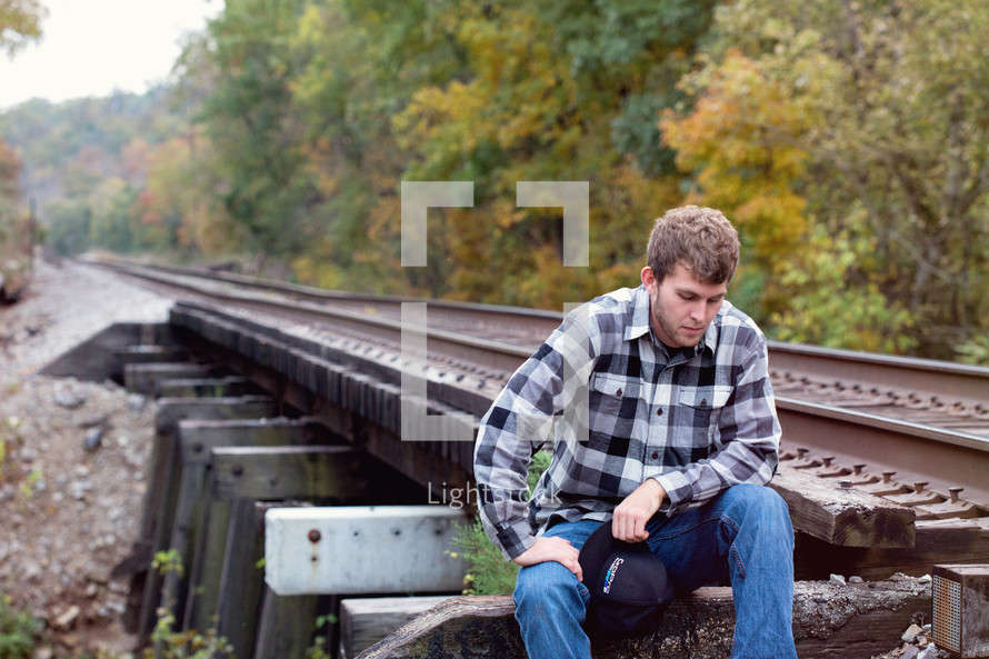 young man sitting on the train tracks 