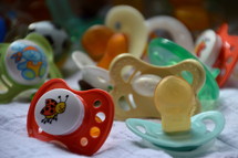 a bunch of pacifiers. 
pacifier, dummy, comforter, baby, toddler, child, little, soother, family, children, kid, kids, new, newborn, young, pacifiers, care, calm, soothe, lull, reassure, comfort, smooth, pacify, quiet, lot, bunch, cluster, different, various, size, form, color, babies, dummies, descendants, descendant, offspring 