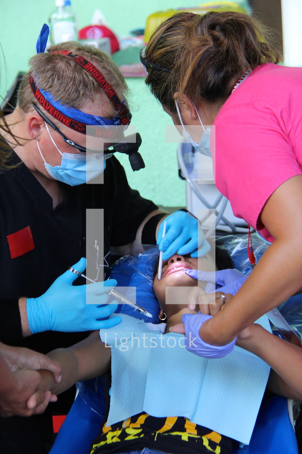 dentist and dental assistant working on a child 