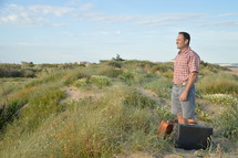 a man standing on a hill with luggage 