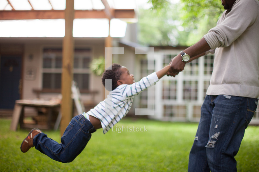 father swinging his son outdoors 
