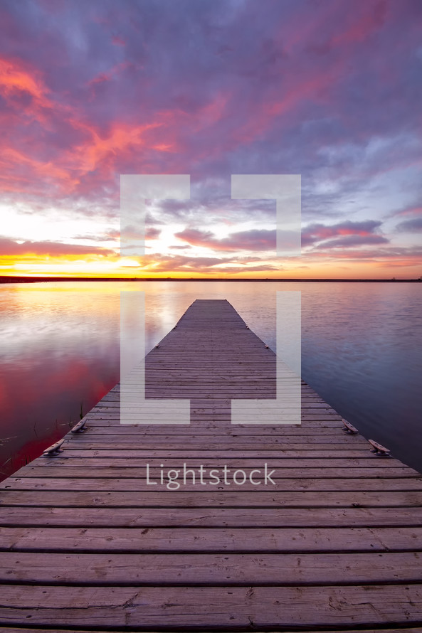 dock over calm water at sunset 