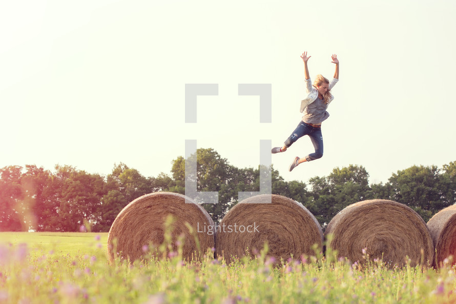 woman jumping on hay bales 